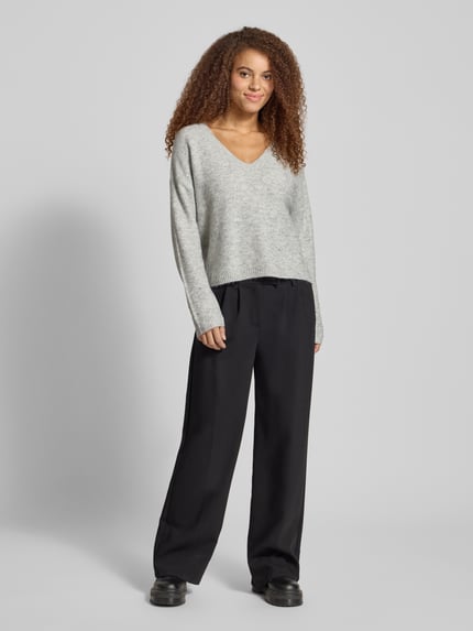 Frauenmodel trägt Regular Fit Strickpullover mit Paillettenbesatz Modell 'ARIZONA' von Only, Melange-Optik, V-Ausschnitt, Langarm, gerippte Abschlüsse, Strick, Ganzkörperansicht von vorne.