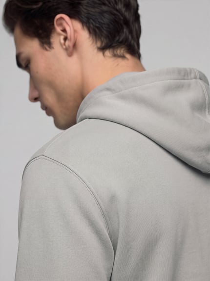 Männermodel trägt Regular Fit Hoodie mit Logo-Patch Modell 'Wetalk' von BOSS Orange in Grau, Jersey- und Rippstruktur, Nahaufnahme Rückansicht.