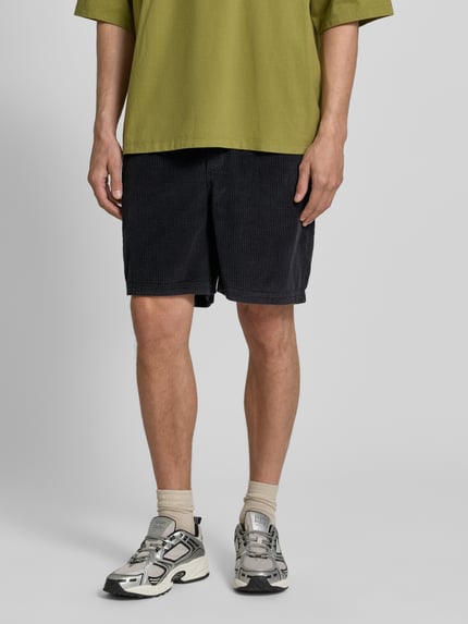 Męski model nosi Shorts mit elastischem Bund Modell 'PADOW' od American Vintage z czarnej bawełny o kroju loose fit, Szerokość w rozmiarze M/L 39 cm, długość nogawki wewnętrznej 15 cm, pełny widok z przodu.