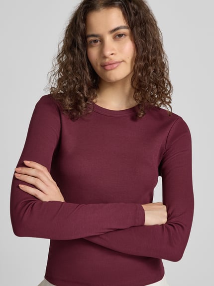 Frauenmodel trägt Slim Fit Langarmshirt aus Baumwoll-Mix Modell 'VAL' von ONLY in Dunkelrot, feine Rippenstruktur, Nahaufnahme Oberkörper. Damen Langarmshirt von ONLY.