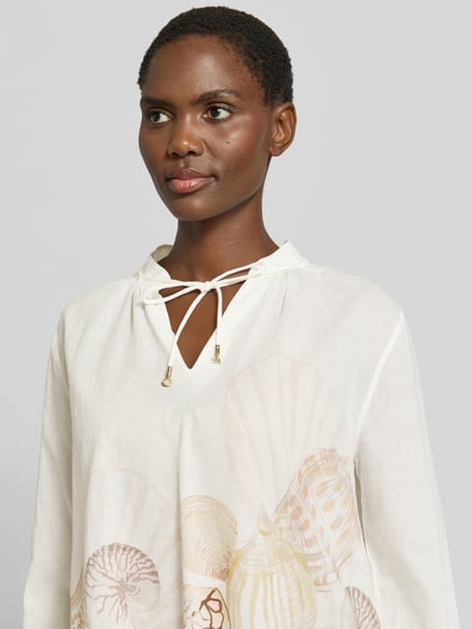 Kobiece modelka ma na sobie Relaxed Fit Bluse mit Schnürung von Marc Cain z bawełny, wzór na całej powierzchni, wiązanie, nahaufnahme górnej części ciała.
