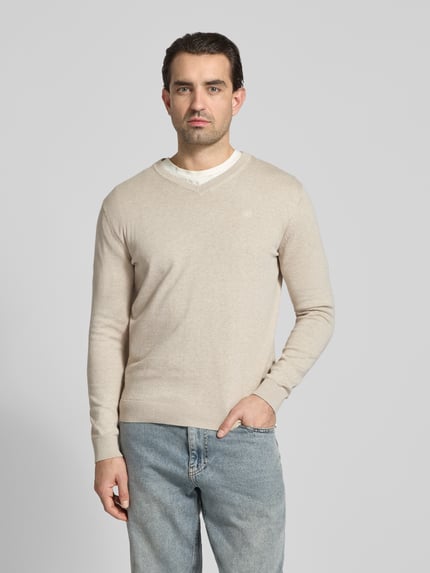 Männermodel trägt Regular Fit Pullover aus reiner Baumwolle von Tom Tailor in Beige, unifarben, Feinstrick, V-Ausschnitt, Ganzkörperansicht von vorne.