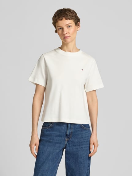 Vrouwenmodel draagt Boxy Fit T-shirt uit puur katoen van Tommy Hilfiger, look: effen kleuren, pasvorm: boxy fit, gestikt logo, ronde hals, korte mouw, materiaalverwerking: interlock, materiaal: puur katoen, voorkant bovenlichaam close-up.