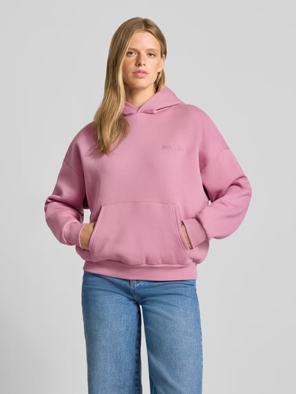 Frauenmodel trägt Relaxed Fit Hoodie aus Baumwoll-Mix mit Label-Detail von REVIEW in Rosa, Känguru-Tasche, elastische Abschlüsse, Ganzkörperansicht von vorne