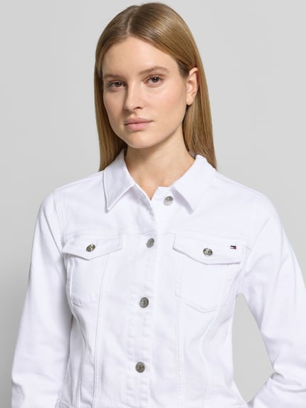 Vrouwenmodel draagt Slim Fit Jeansjacke aus Baumwoll-Mix van Tommy Hilfiger in witte denimlook, twill, borstzakken, knoopsluiting, logostitching, katoenmix, detailopname bovenlichaam.