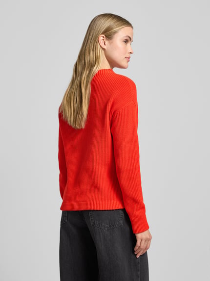 Frauenmodel trägt Strickpullover mit Stehkragen und Tunnelzug von Jake*s Casual, Reine Baumwolle, Regular-Fit, Rückenlänge 67 cm, Ärmellänge 56 cm, knalliges Rot, grobe Strickstruktur, Ganzkörperansicht Rückansicht.