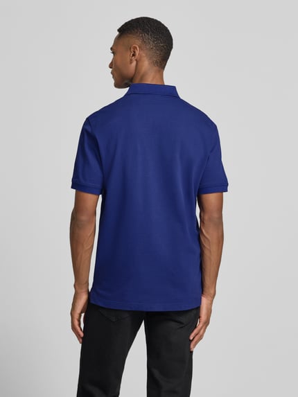 Männermodel trägt Regular Fit Poloshirt mit Logo-Stitching von Gant aus elastischem Baumwoll-Mix in Blau, Ganzkörperansicht Rückansicht.