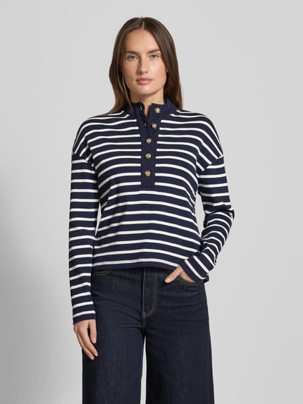 Vrouwenmodel draagt 'Ringel Polo Shirt mit Schmuckknopf' van Christian Berg Woman in navy-wit gestreept, geribbelde staande kraag, korte knopenlijst, losse pasvorm, vooraanzicht heuphoogte.