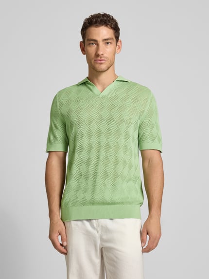 Männermodel trägt Regular Fit Poloshirt aus reiner Baumwolle Modell 'ARCO' von SELECTED HOMME in Hellgrün mit Lochstrickmuster, Ganzkörperansicht von vorne.