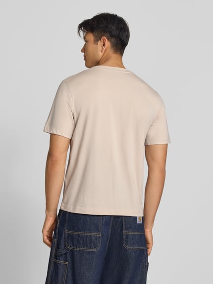 Męski model nosi T-Shirt mit Label-Print und Rundhalsausschnitt von JACK & JONES z czystej bawełny, krój regular fit, długość tyłu 68 cm, kolor jasny beż, gładka faktura, widok całej sylwetki od tyłu.
