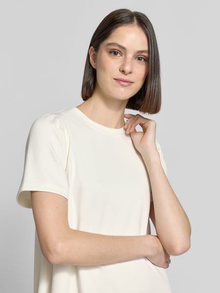 Frauenmodel trägt T-Shirt-Kleid aus Modal-Mix von Rich & Royal in Creme mit Rundhalsausschnitt, Gerader-Schnitt, Nahaufnahme Oberkörper. Rückenlänge 83 cm, Brustweite 40 cm, Ärmellänge 24 cm, Stretch-Anteil, Minikleid.