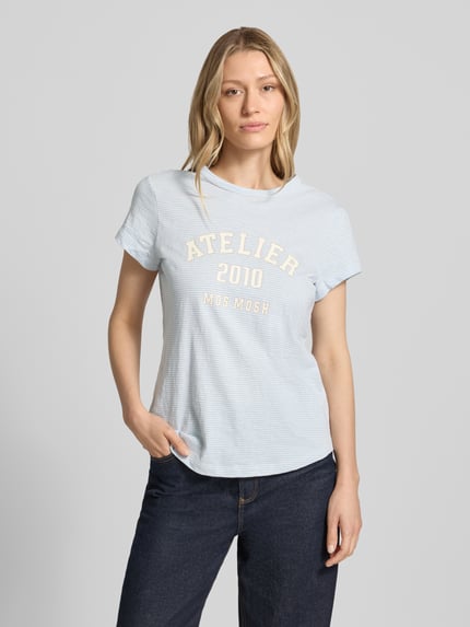 Vrouwenmodel draagt Regular Fit T-shirt met logoprint van MOS MOSH in lichtblauw, puur katoen, ronde hals, ruglengte maat S 63 cm, Ganzkörperansicht von voren.