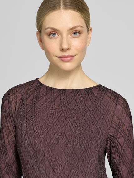 Frauenmodel trägt Midikleid im Allover-Look Modell 'POMEL' von MANGO, Rundhalsausschnitt, strukturierte Oberfläche, Nahaufnahme Oberkörper.