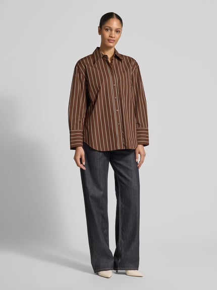 Frauenmodel trägt Relaxed Fit Hemdbluse mit Brusttasche Modell 'LLAMA' von Mango, braun mit weißen Streifen, reine Baumwolle, Ganzkörperansicht von vorne.