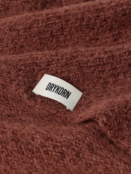 Produktfoto, Dreieckstuch mit Woll-Anteil von DRYKORN in rötlich-brauner Strick-Optik, sichtbarer Label-Patch, Material-Mix, Detailaufnahme.