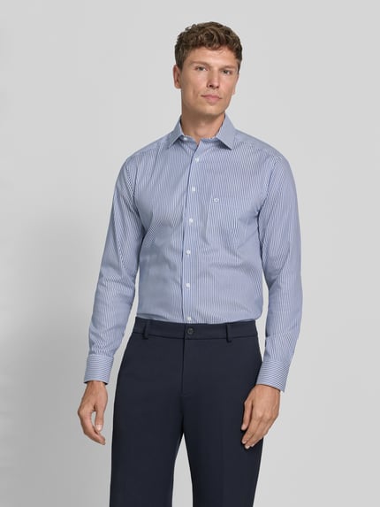 Männermodel trägt Regular Fit Businesshemd mit Brusttasche von OLYMP, feine blaue Streifen, Kentkragen, Webware, Ganzkörperansicht von vorne.