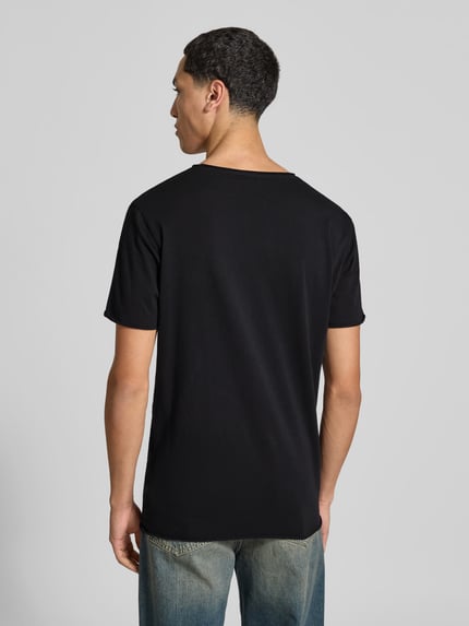 Męski model nosi T-Shirt mit Rollsaum od Filippa K, czarna bawełna, prosty krój, okrągły dekolt, długość tyłu w rozmiarze M: 70 cm, całopostaciowy widok z tyłu.
