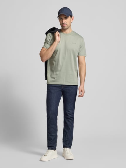 Männermodel trägt T-Shirt mit Rundhalsausschnitt von CK Calvin Klein aus Baumwoll-Mix in Regular Fit, dezentes Grün, Ganzkörperansicht von vorne.