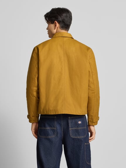 Männermodel trägt Jacke mit Label-Stitching und Eingrifftaschen von BLKVIS in Senfgelb, reine Baumwolle, Regular Fit, Ganzkörperansicht Rückansicht.