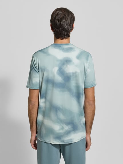 Männermodel trägt T-Shirt im Allover-Look mit Logo von Under Armour in Blau- und Grautönen, Material-Mix mit Stretch, Ganzkörperansicht Rückansicht.