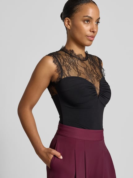 Frauenmodel trägt Body mit Spitzenbesatz von Rinascimento, enganliegend, Stehkragen, Spitze oben, Bordeaux-Rock, Nahaufnahme Oberkörper.