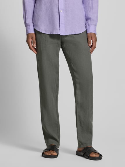 Männermodel trägt Straight Fit Leinenhose aus reinen Leinen Modell 'Lynx' von Mmx, graugrün, glatte Textur, Ganzkörperansicht von vorne. Herren Leinenhose, Gesäßtaschen, Knopf- und Reißverschluss, Bundweite 43 cm, Innenbeinlänge 81 cm bei Größe 32/32.