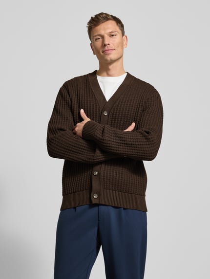Männermodel draagt Regular Fit Strickjacke aus reiner Baumwolle Modell 'TOM' van SELECTED HOMME, bruin, wafelstructuur, grofgebreid, knoopsluiting, lange mouwen, geribde boorden, voorkant, nahaufnahme bovenlichaam.