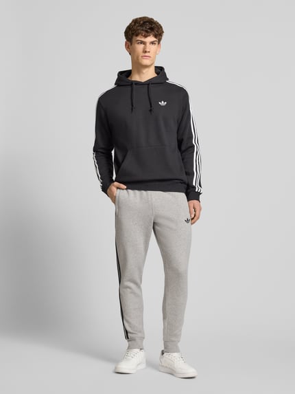 Mannelijk model draagt Sweatpants mit elastischem Bund van adidas Originals in grijs, los fit, katoenmengsel, label-stitching, steekzakken, elastische tailleband, volledige lichaamsaanzicht van voren