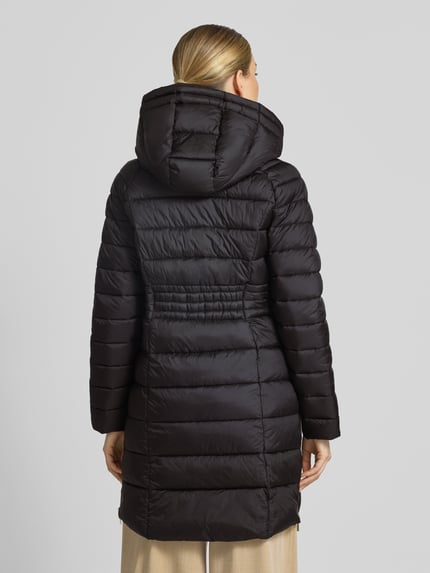 Vrouwenmodel draagt gewatteerde mantel met ritssluitzakken en capuchon van MICHAEL Michael Kors in zwart, recht model, rugaanzicht. Ruglengte maat S: 87 cm, schouderbreedte: 45 cm, borstwijdte: 52 cm, mouwlengte: 59 cm.