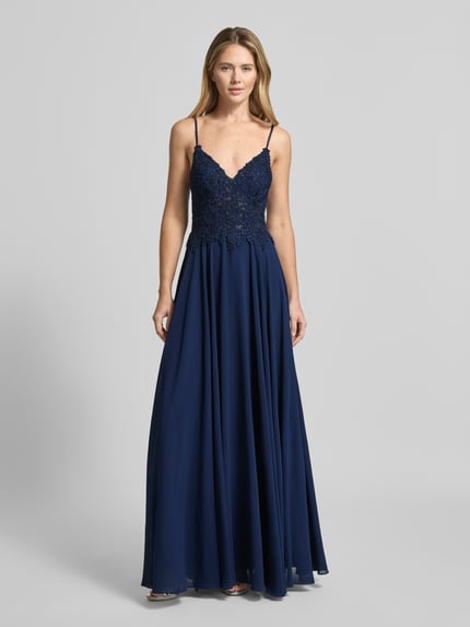 Frauenmodel trägt Regular Fit Abendkleid mit Strasssteinbesatz von Mascara in Dunkelblau mit Spitzenbesatz, A-Linie, Spaghettiträgern, semitransparentem Design, Ganzkörperansicht von vorne.