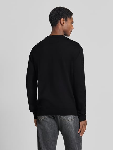 Männermodel trägt zwarte katoenen trui Regular Fit Pullover aus reiner Baumwolle model 'LOUKAA' van ARMEDANGELS, Ganzkörperansicht Rückansicht.