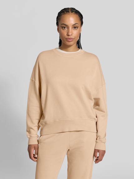 Frauenmodel trägt Oversized Sweatshirt aus Baumwoll-Mix von Juvia in Beige, gerippte Abschlüsse, Rundhalsausschnitt, Fleece-Innenseite, Ganzkörperansicht von vorne.