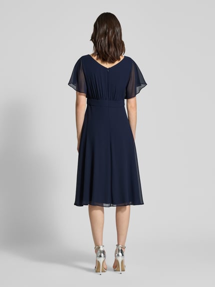 Vrouwenmodel draagt Knielanges Kleid mit Rundhalsausschnitt van Vera Mont in diepblauw, semi-transparant design, getailleerde fit, korte mouwen, ondoorzichtige onderjurk, ruglengte 102 cm, borstwijdte 37 cm, mouwlengte 27 cm, volledige achteraanzicht.