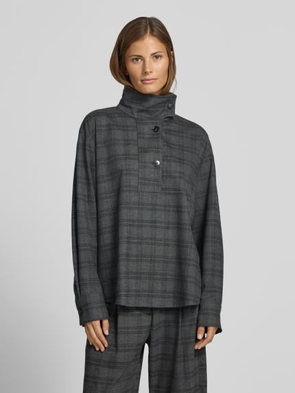 Frauenmodel trägt Bluse mit Stehkragen und kurzer Knopfleiste von Style Icon Collection, grau kariert mit abgerundetem Saum, Ganzkörperansicht von vorne.