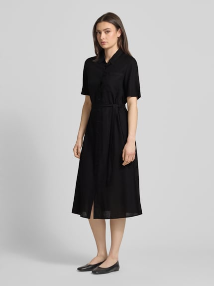 Frauenmodel trägt figurumspielendes Freizeitkleid aus Viskose-Leinen-Mix Modell 'PIA' von Pieces, unifarben schwarz, Midi-Länge, V-Ausschnitt, Knopfleiste, kurzarm, Brusttasche, glatte Flammgarn-Textur, Ganzkörperansicht von vorne.