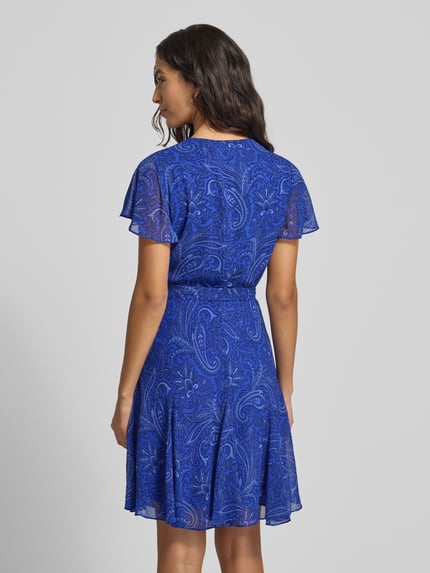 Frauenmodel trägt Knielanges Kleid mit V-Ausschnitt Modell 'WANDELLA' von Lauren Ralph Lauren in intensivem Blau mit Paisley-Muster, Taillierter Schnitt, Wickel-Optik, Taillengürtel, blickdichtes Unterkleid, Rückenlänge bei Größe 36: 96 cm, Ganzkörperansicht Rückansicht.