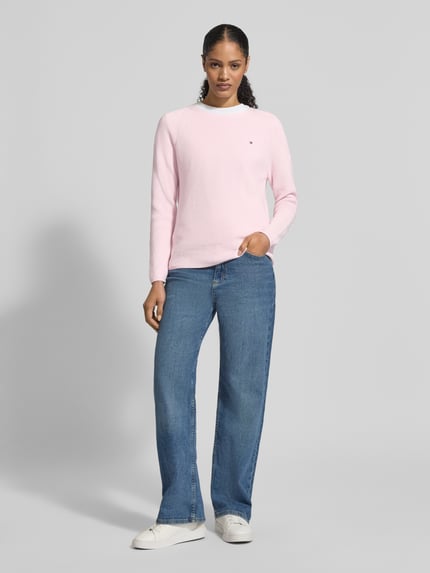 Frauenmodel trägt Regular Fit Pullover aus reiner Baumwolle von Tommy Hilfiger in Rosa, unifarben, Rippstrick, Logo-Stitching, Ganzkörperansicht von vorne.