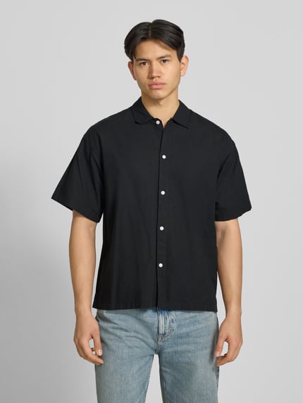 Männermodel trägt schwarzes Regular Fit Freizeithemd aus Baumwoll-Leinen-Mix von Jack & Jones, Kentkragen, Knopfleiste, Ganzkörperansicht von vorne.