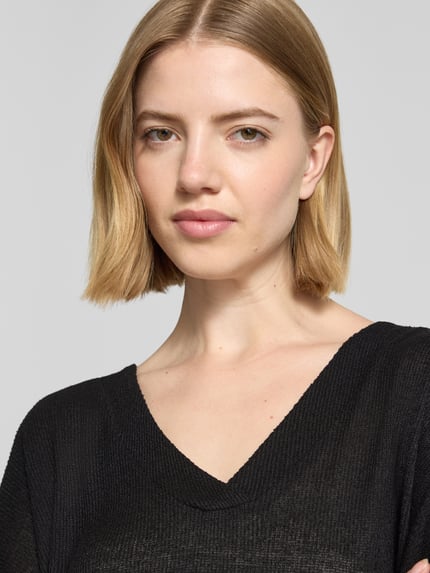 Frauenmodel trägt Strickshirt mit V-Ausschnitt Modell 'Delia' von Soyaconcept, schwarzer Viskose-Mix mit Stretch-Anteil, Nahaufnahme Oberkörper.