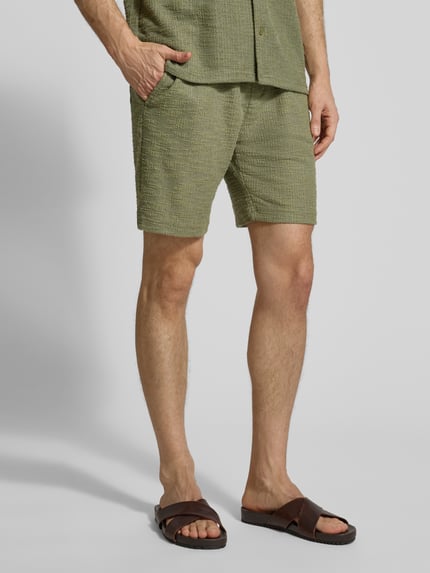 Männermodel trägt Shorts mit elastischem Bund von MCNEAL in Grün mit Strukturmuster aus Material-Mix, Regular-Fit, Nahaufnahme Unterkörper.