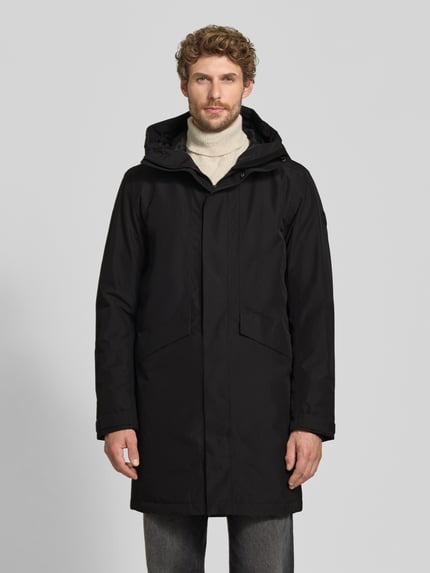 Männermodel trägt Regular Fit Parka mit Kapuze Modell 'Kenny' von Didriksons in Schwarz, gerade Form, Eingrifftaschen, Ganzkörperansicht von vorne. Rückenlänge 99 cm, Schulterbreite 48 cm, Brustweite 59 cm, Ärmellänge 72 cm.