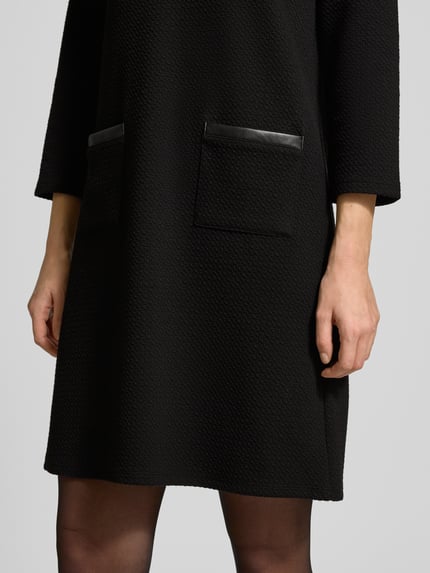 Vrouwenmodel draagt Mini-jurk met 3/4-mouwen van More & More, katoenmix, getailleerd model, steekzakken, gestructureerde stof, detailopname.