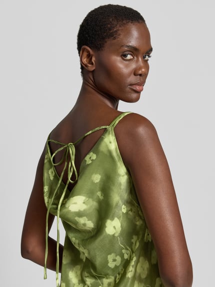 Frauenmodel trägt Schmales Freizeitkleid aus Viskose-Mix Modell 'GIONA' von Selected Femme mit florales-Batik Allover-Muster, Satin-Optik in grün, Maxi-Länge, ärmellos, Wasserfall-Ausschnitt, Materialverarbeitung: Satin, Nahaufnahme Rückansicht.