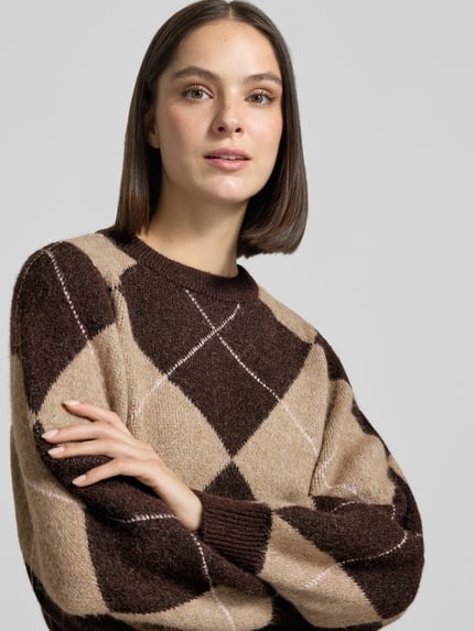 Frauenmodel trägt Pullover mit Ballonärmeln von VERO MODA in Braun-Beige mit Argyle-Muster, Strickstruktur, Nahaufnahme Oberkörper.