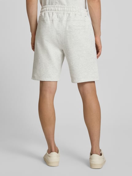 Männermodel trägt Sweatshorts mit Label-Stitching Modell 'Lido' von PEGADOR, Baumwoll-Mix, helle Farbe, Regular Fit, Ganzkörperansicht Rückansicht.