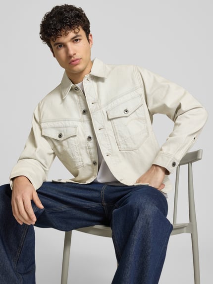 Männermodel trägt Jeansjacke mit Brusttaschen Modell 'Dakota' von G-Star Raw aus Reine Baumwolle, Relaxed-Fit, cremefarben, Nahaufnahme Oberkörper.