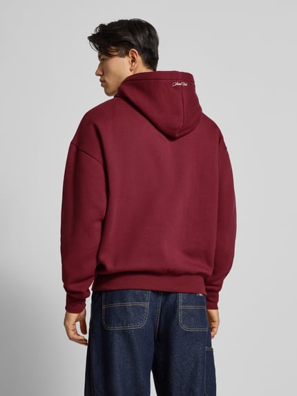 Männermodel trägt Hoodie mit Kapuze von PROHIBITED in Dunkelrot, lockerer Schnitt, Känguru-Tasche, Rückenansicht, Ganzkörperansicht Rückansicht.