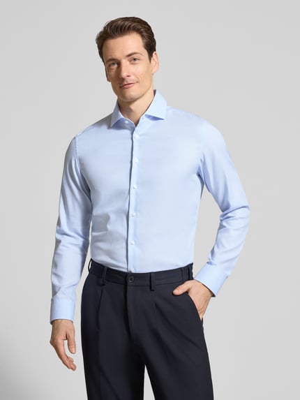 Męski model nosi Slim Fit Business-Hemd aus Baumwolle mit Kentkragen od SEIDENSTICKER, jasnoniebieska, delikatnie teksturowana, guziki, krój slim fit, bawełna, widok całej sylwetki z przodu, długość tyłu w rozmiarze 40: 70 cm, szerokość w rozmiarze 40: 45 cm, długość rękawa w rozmiarze 40: 65 cm.