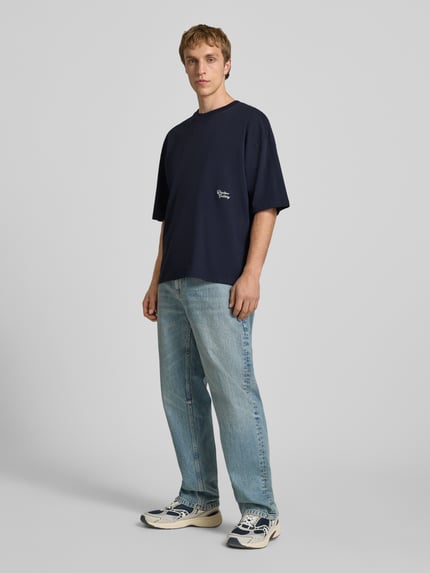 Männermodel trägt T-Shirt mit Stitching und Rundhalsausschnitt von REVIEW in Dunkelblau zu Jeans, Oversized, Ganzkörperansicht von vorne