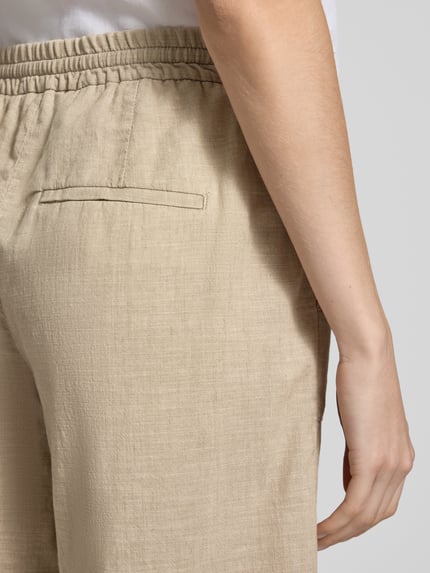 Vrouwenmodel draagt bermuda van puur katoen in beige met elastische band, trekkoord, steekzakken en strookzak; model 'Lia Urban' van Angels, detailopname heup.